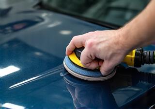 Technician polishing a car hood.